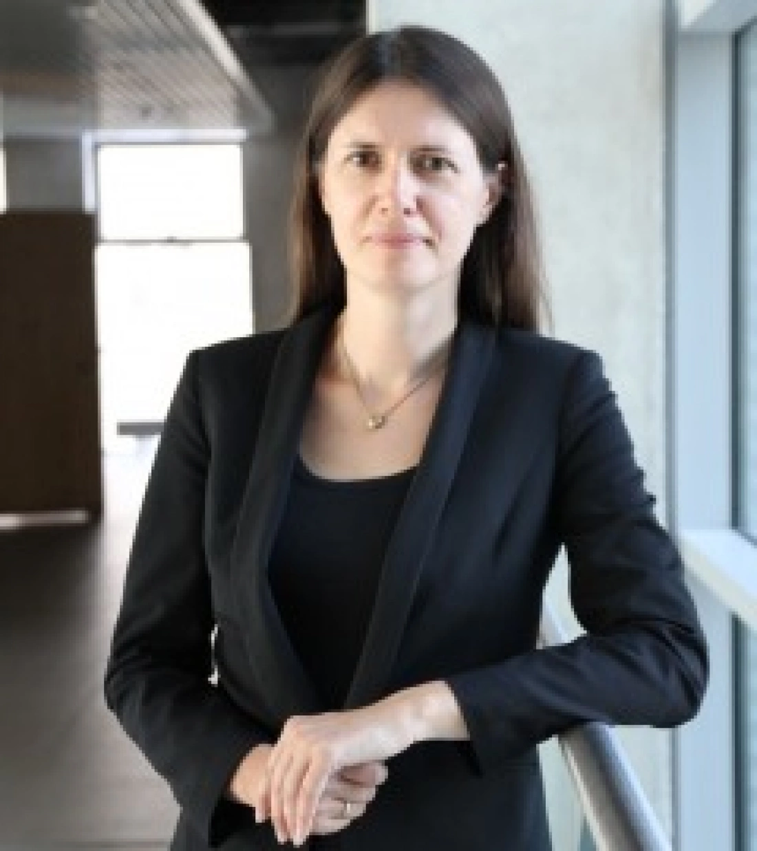 Kobieta w czarnym żakiecie stoi przy balustradzie w nowoczesnym wnętrzu.