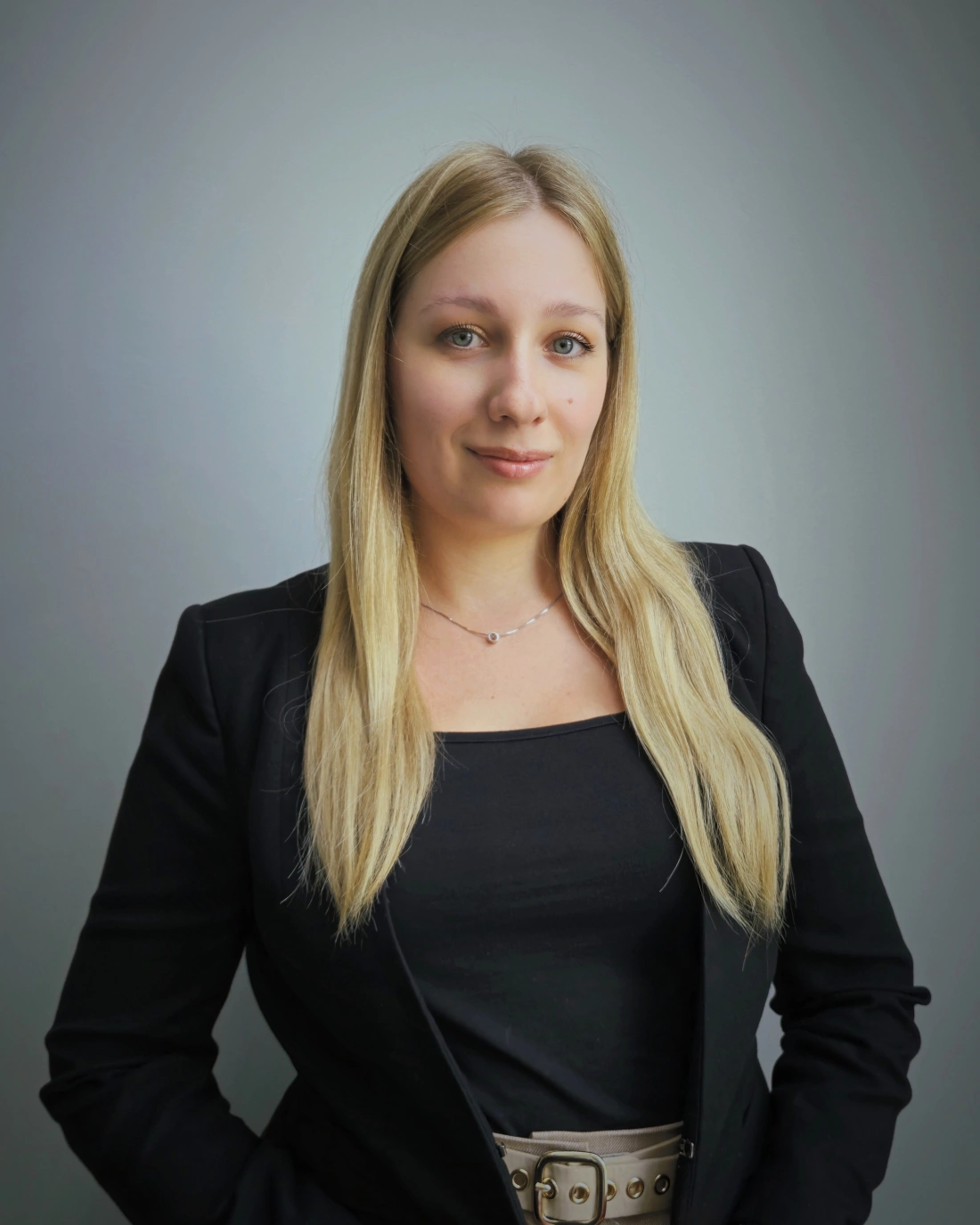 Młoda kobieta w koszuli w zebry, uśmiechająca się z założonymi rękami.