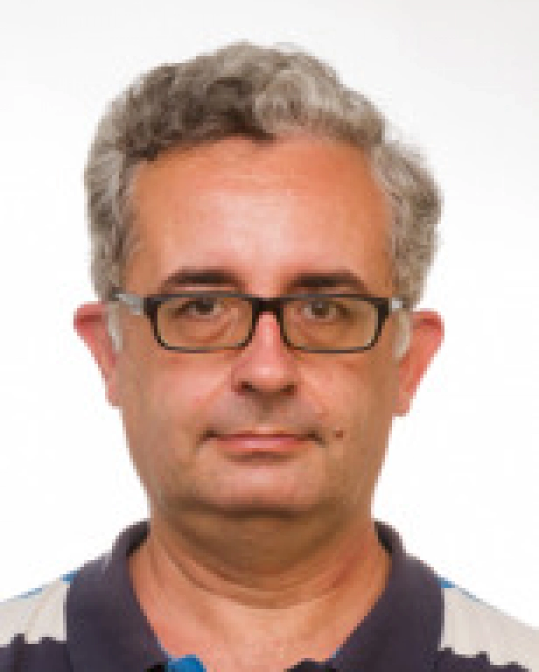 Mężczyzna w okularach, o siwych włosach, z neutralnym wyrazem twarzy.