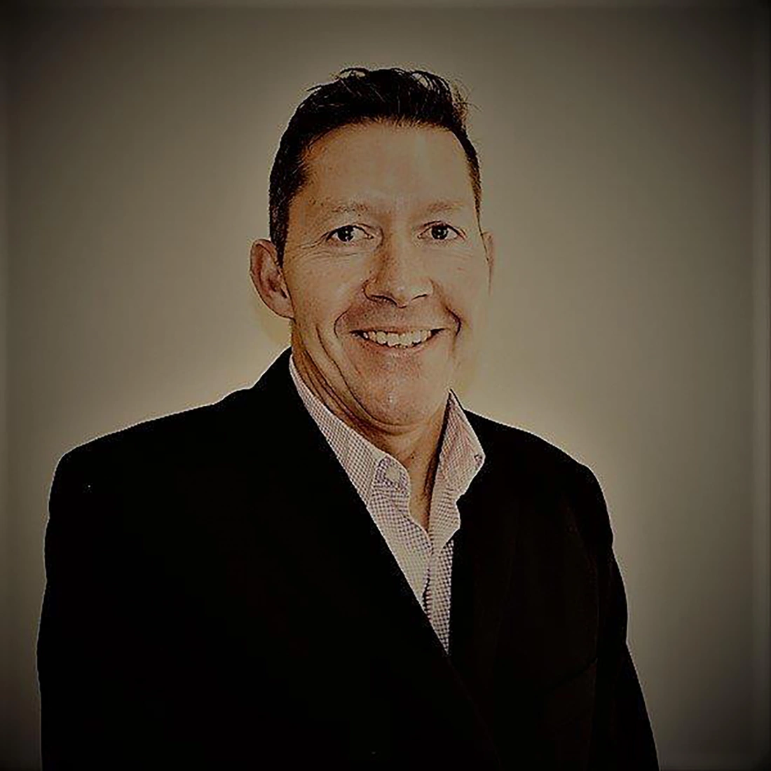 Mężczyzna w garniturze uśmiechający się do kamery.