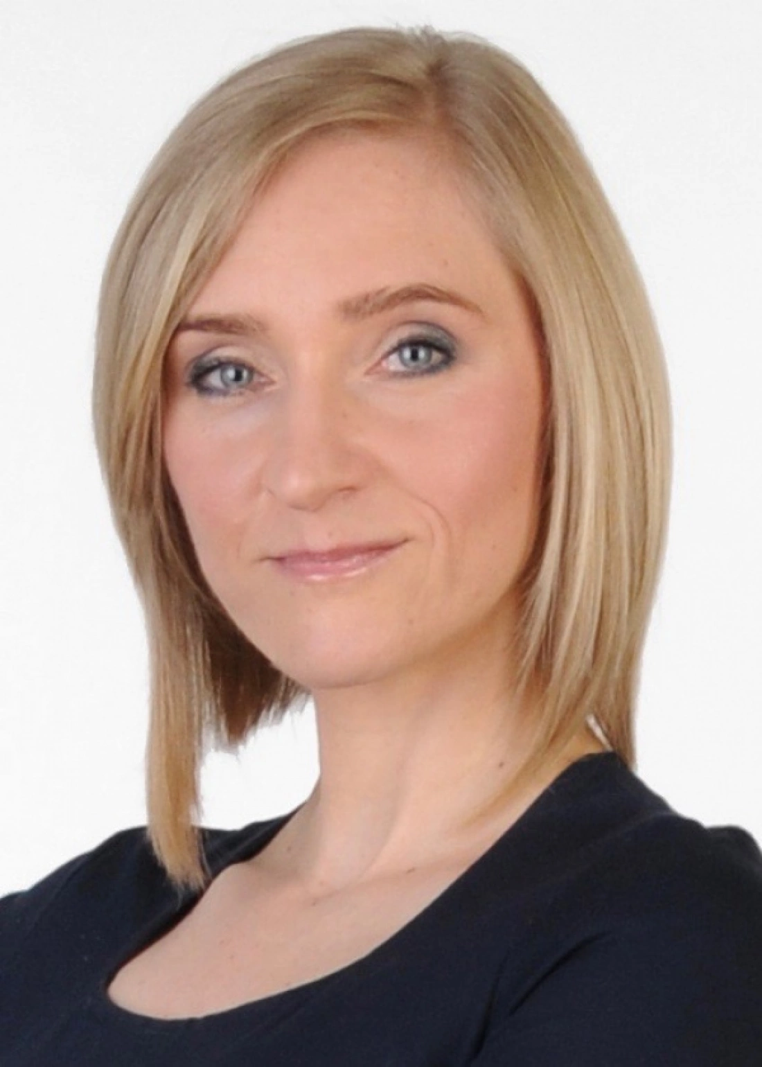 Portret kobiety z krótkimi, blond włosami, uśmiechającej się.