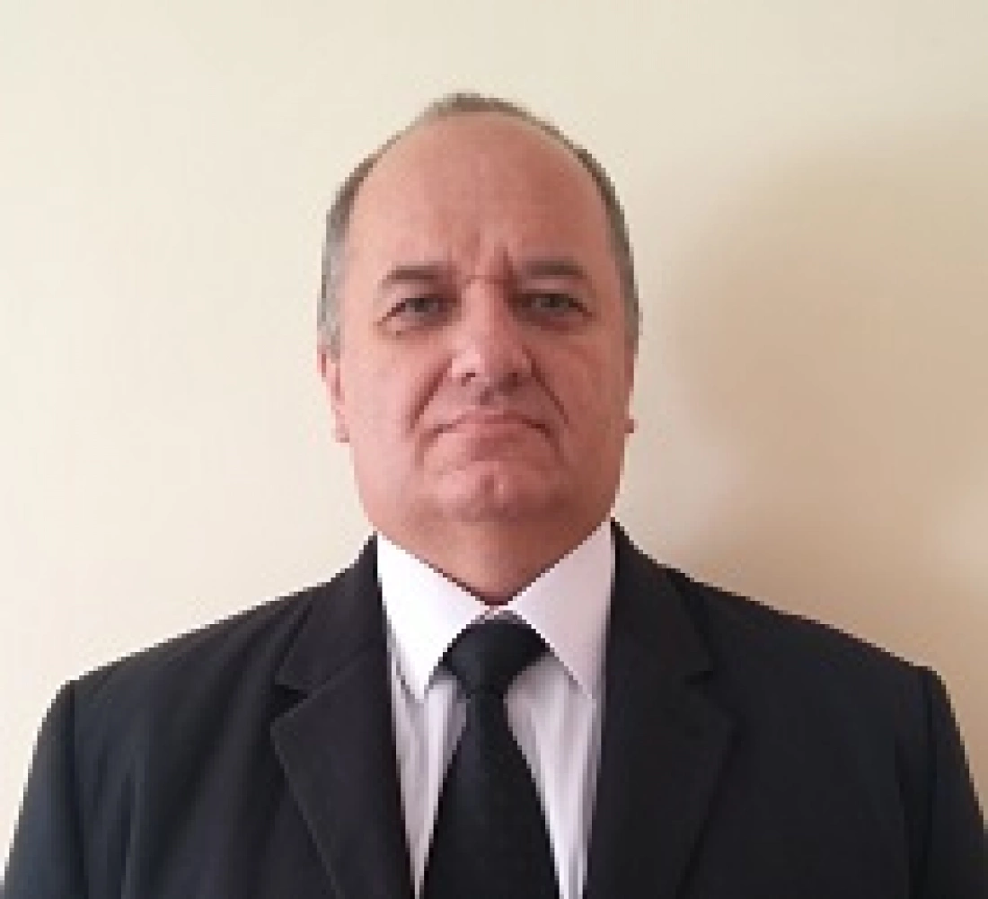 Mężczyzna w eleganckim garniturze stojący przed jasną ścianą.