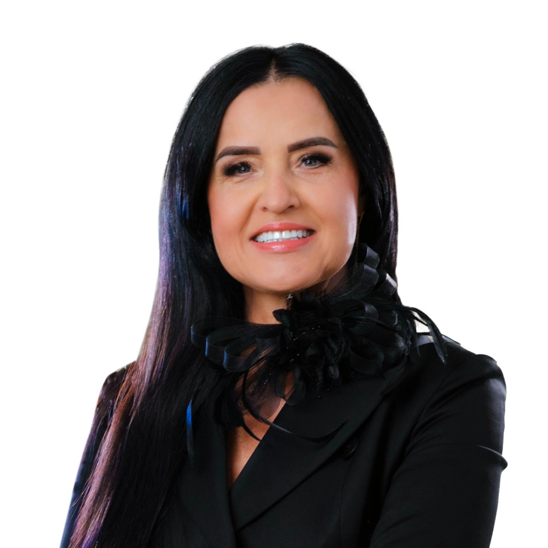 Kobieta o długich, ciemnych włosach, uśmiechająca się w eleganckiej czarnej marynarce z ozdobą.