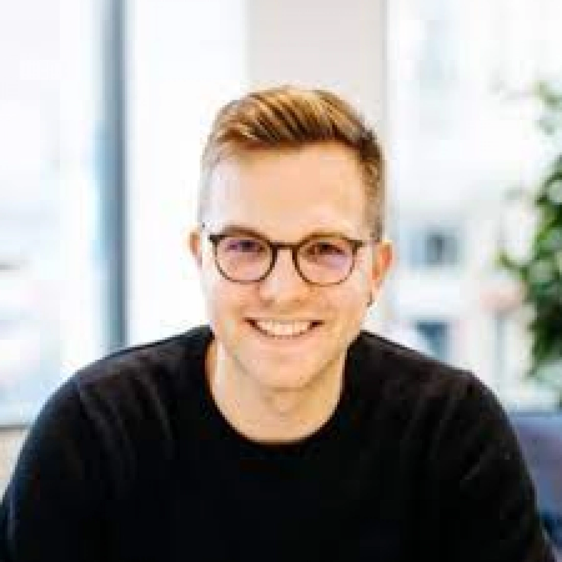 Mężczyzna z okularami uśmiecha się w biurze.