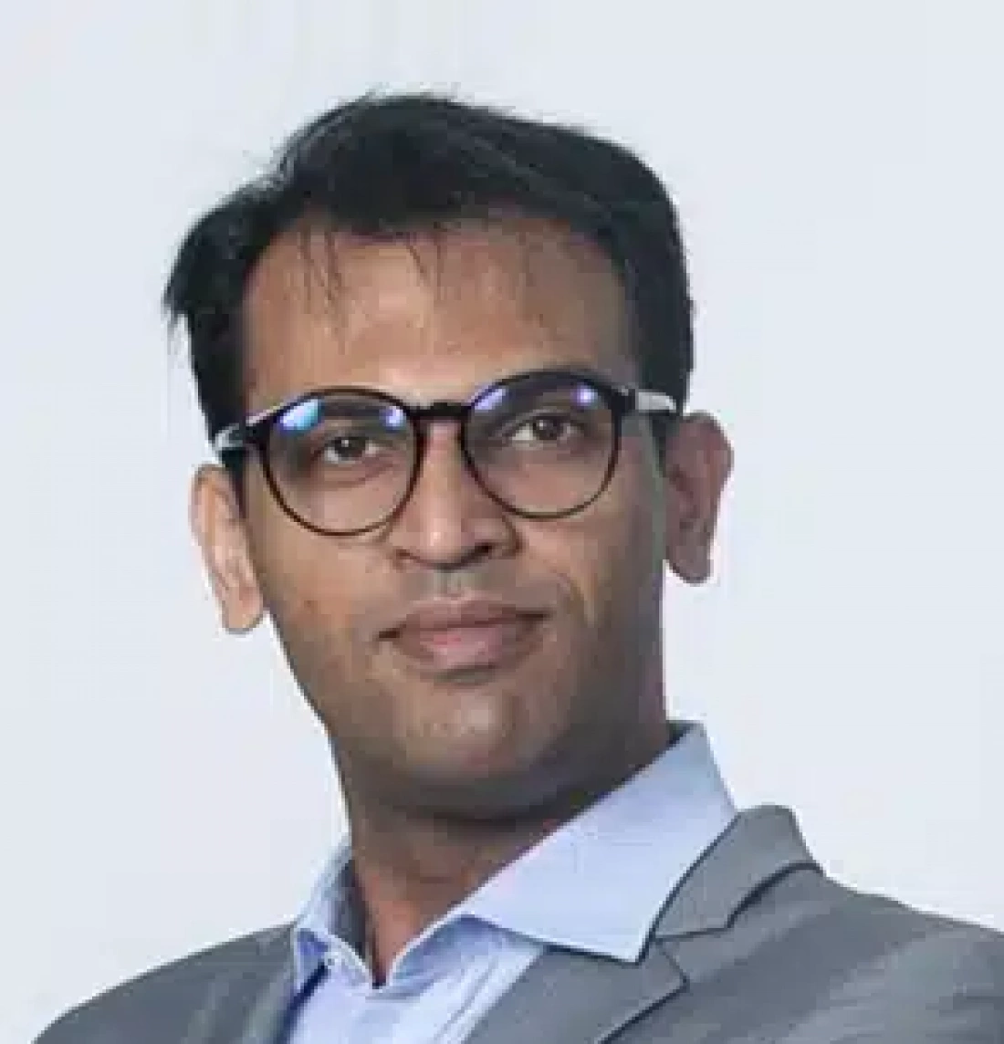 Mężczyzna w okularach, w garniturze, z pewnym wyrazem twarzy.