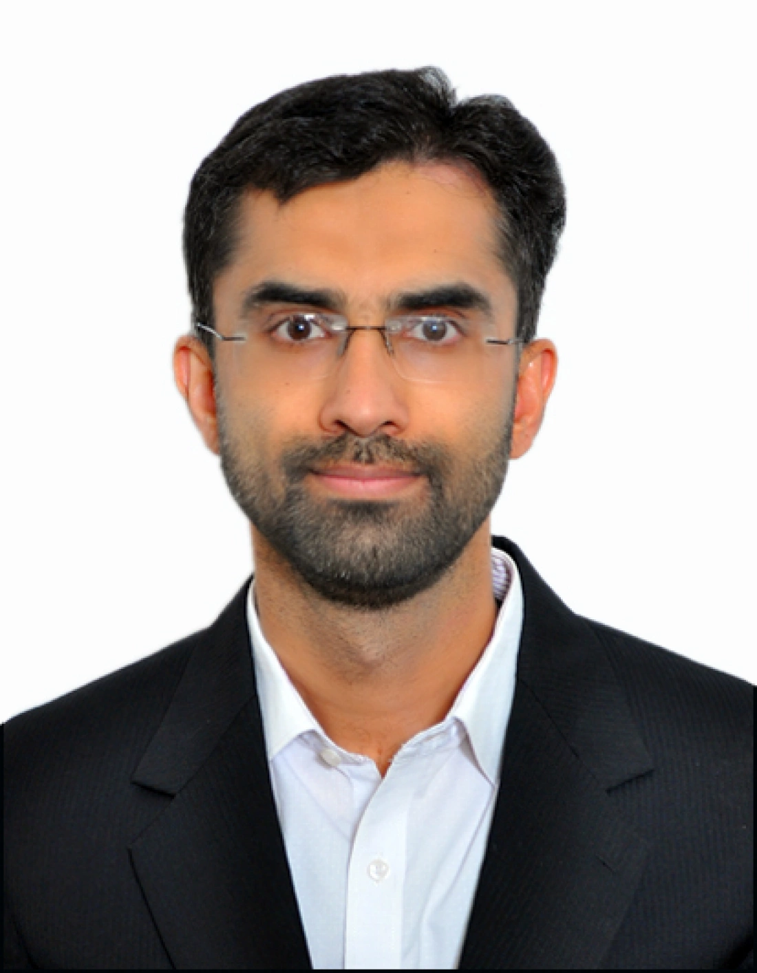 Mężczyzna w okularach, ubrany w elegancki garnitur, patrzy w kamerę.