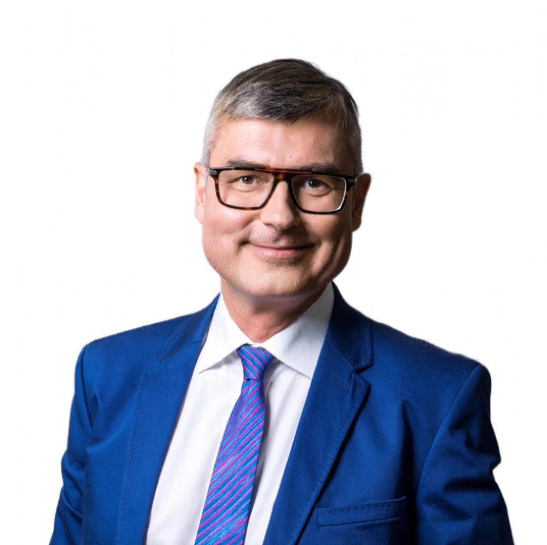 Mężczyzna w okularach, ubrany w niebieski garnitur i kolorową krawatę, uśmiecha się do kamery.