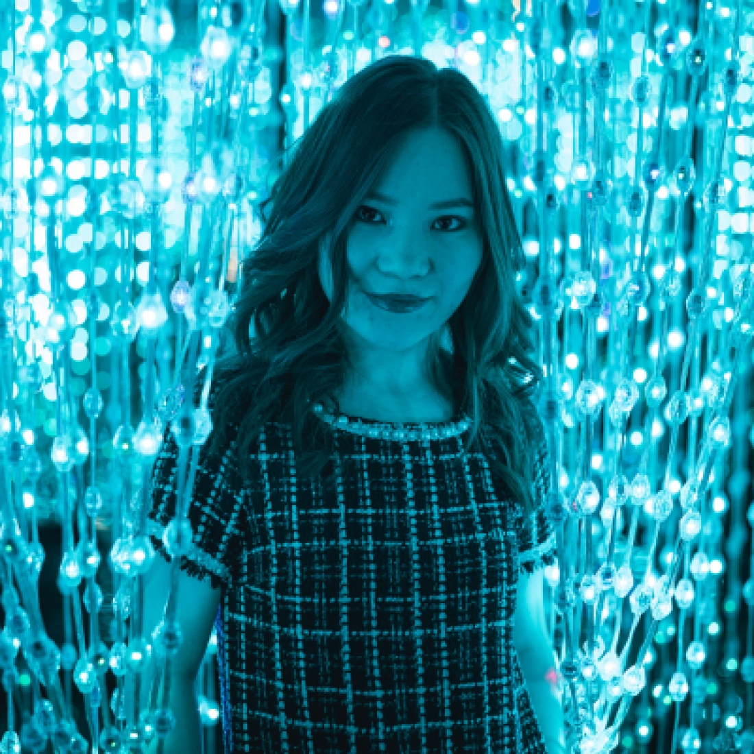 Kobieta pozująca przed tłem z migoczącymi niebieskimi światełkami.