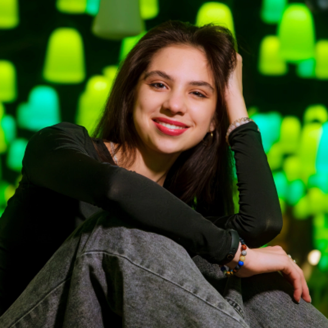 Młoda kobieta uśmiechająca się na tle kolorowych, świecących lamp.