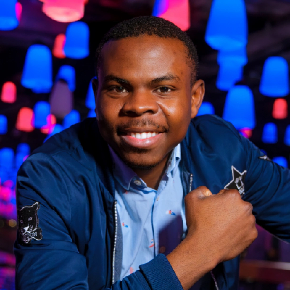 Mężczyzna z uśmiechem w otoczeniu kolorowych lamp.