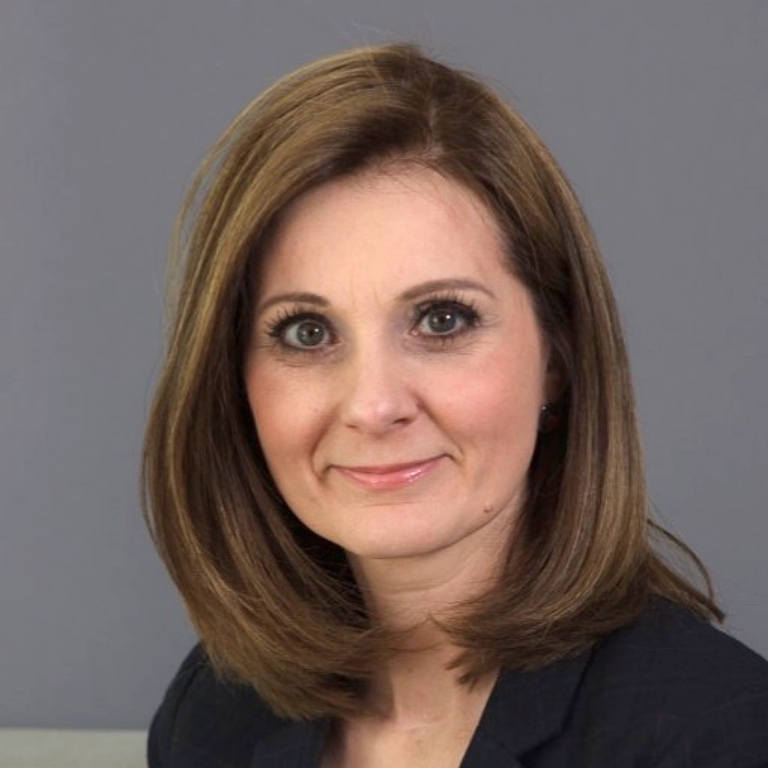 Kobieta z krótkimi brązowymi włosami, uśmiechająca się do kamery.