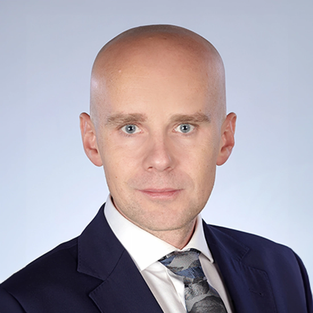 Mężczyzna w garniturze z odkrytą głową, patrzący prosto w kamerę.