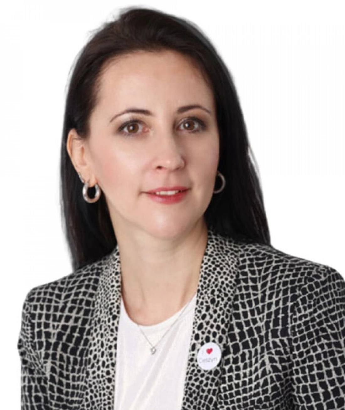 Kobieta w eleganckim żakiecie z biżuterią, uśmiechająca się na tle białym.