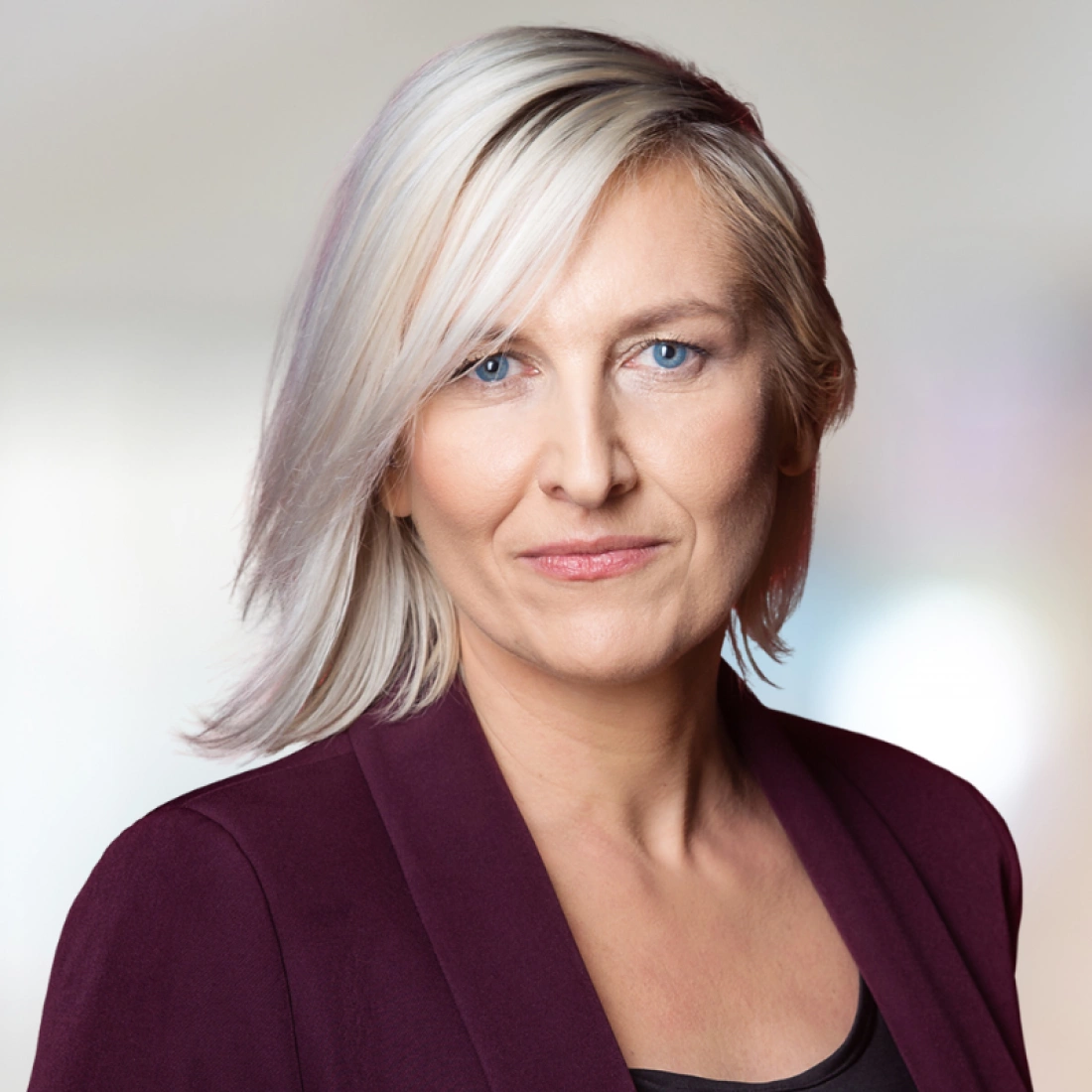 Portret kobiety z jasnymi włosami w eleganckim ubraniu.