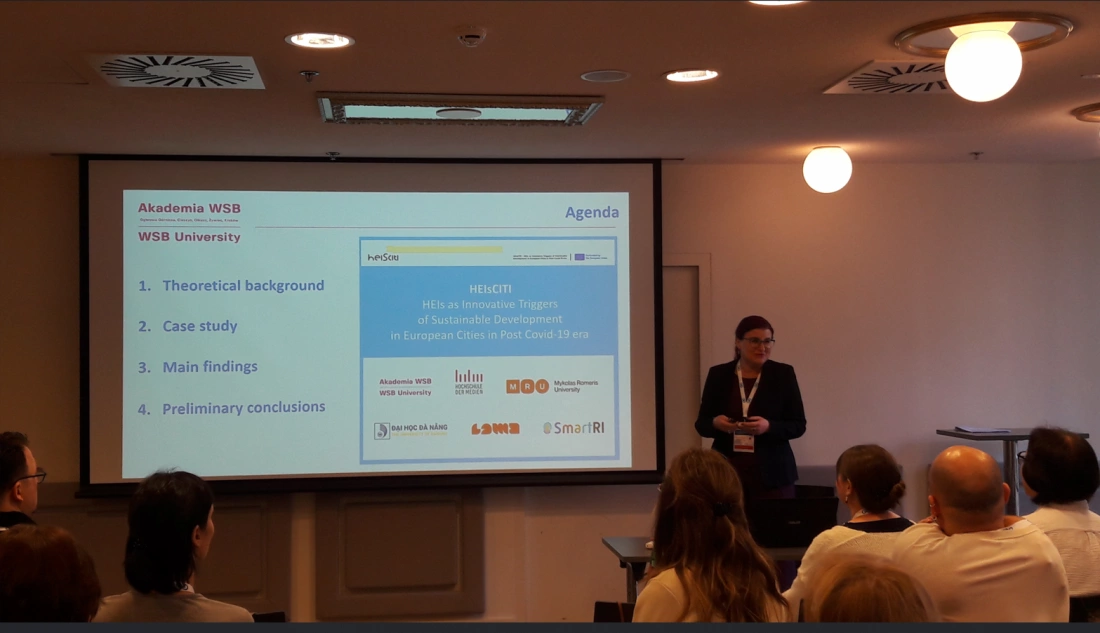 Prezentacja na temat innowacyjnych uczelni jako czynników zrównoważonego rozwoju, z widoczną kobietą przemawiającą do publiczności.