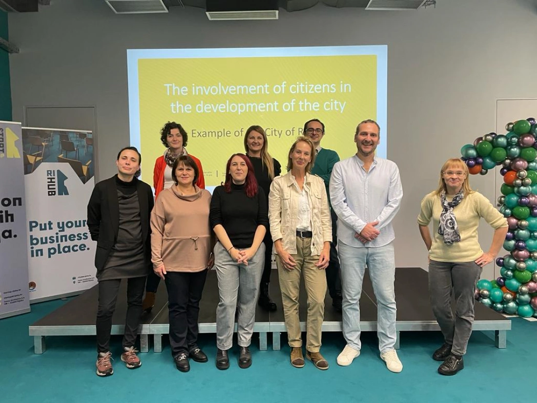 Grupa osób pozująca do zdjęcia na tle prezentacji dotyczącej zaangażowania obywateli w rozwój miasta.