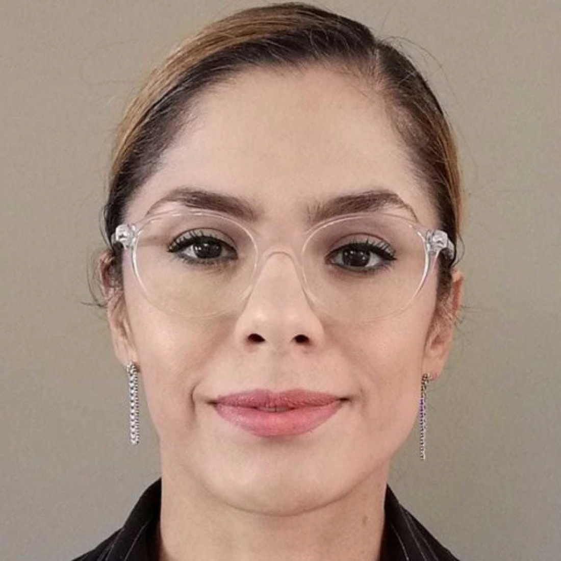 Kobieta w okularach, z ułożonymi włosami, prezentująca neutralny wyraz twarzy.