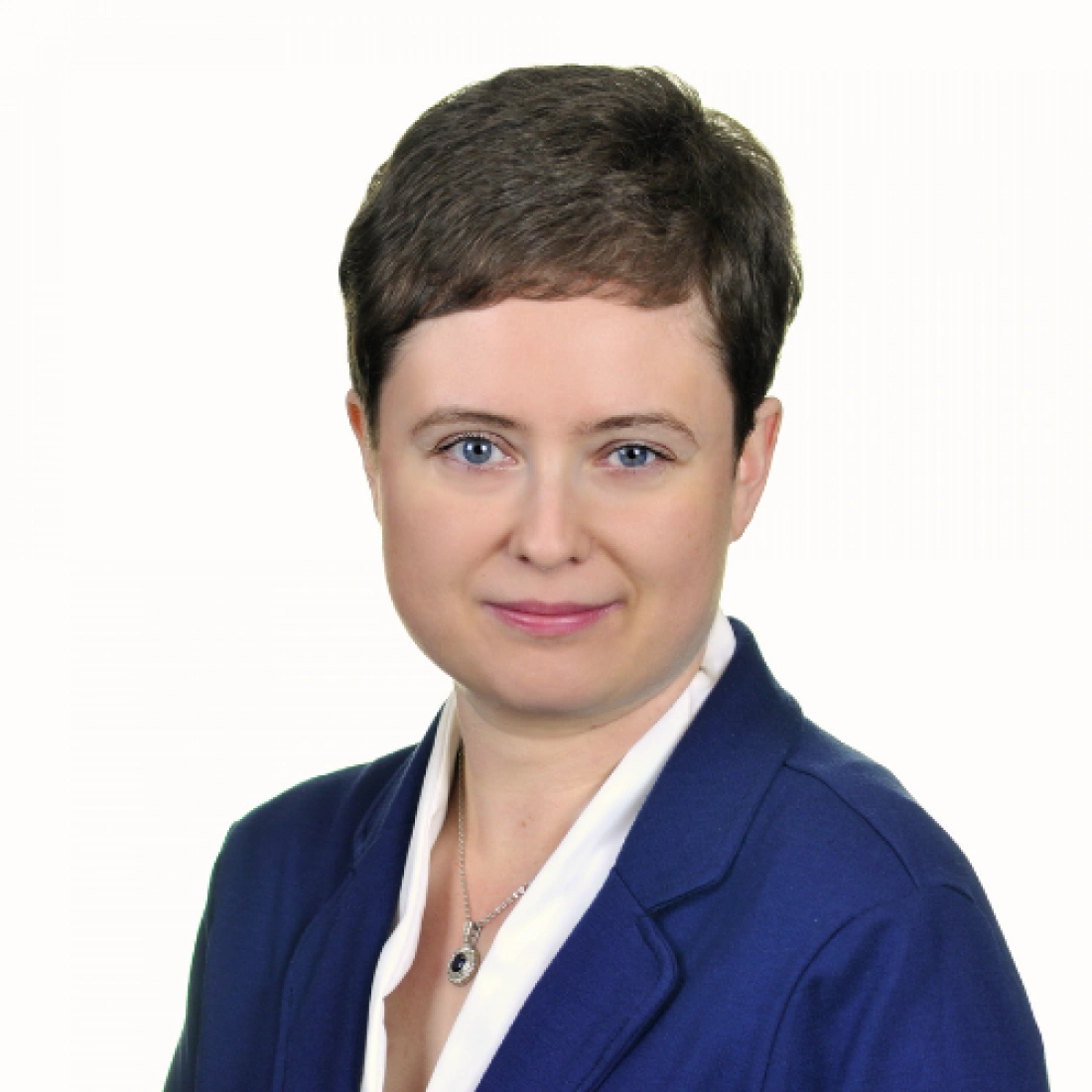 Portret osoby w granatowym garniturze z krótkimi włosami i biżuterią.