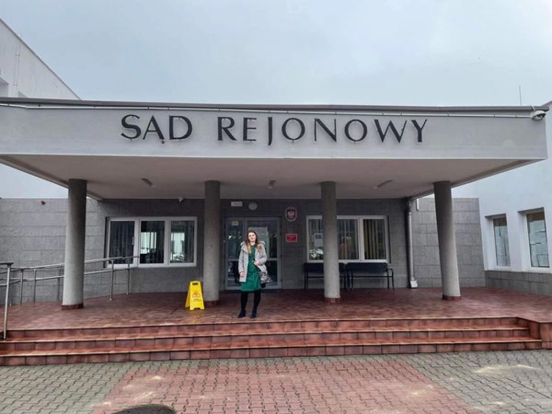 Kobieta stoi przed budynkiem sądu rejonowego.