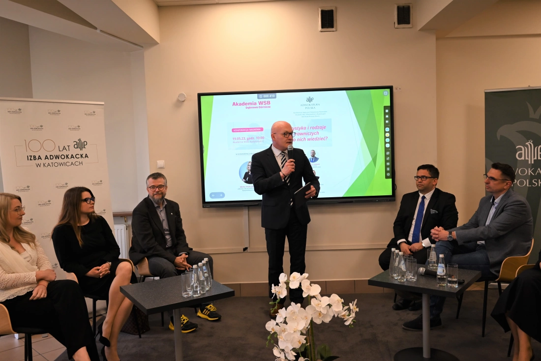Spotkanie na temat prawnych aspektów w Katowicach, z mówcą przy mównicy i panelistami siedzącymi obok.