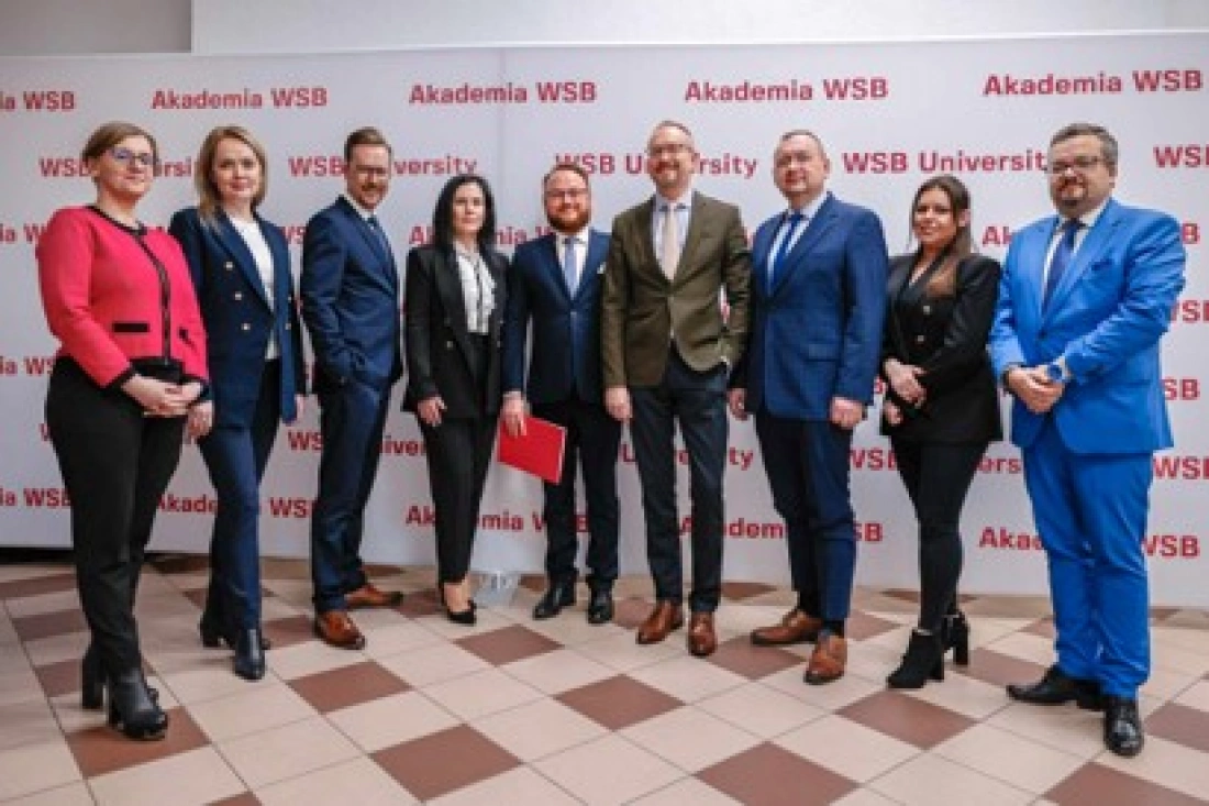Grupa osób stoi razem przed bannerem z napisem "Akademia WSB".