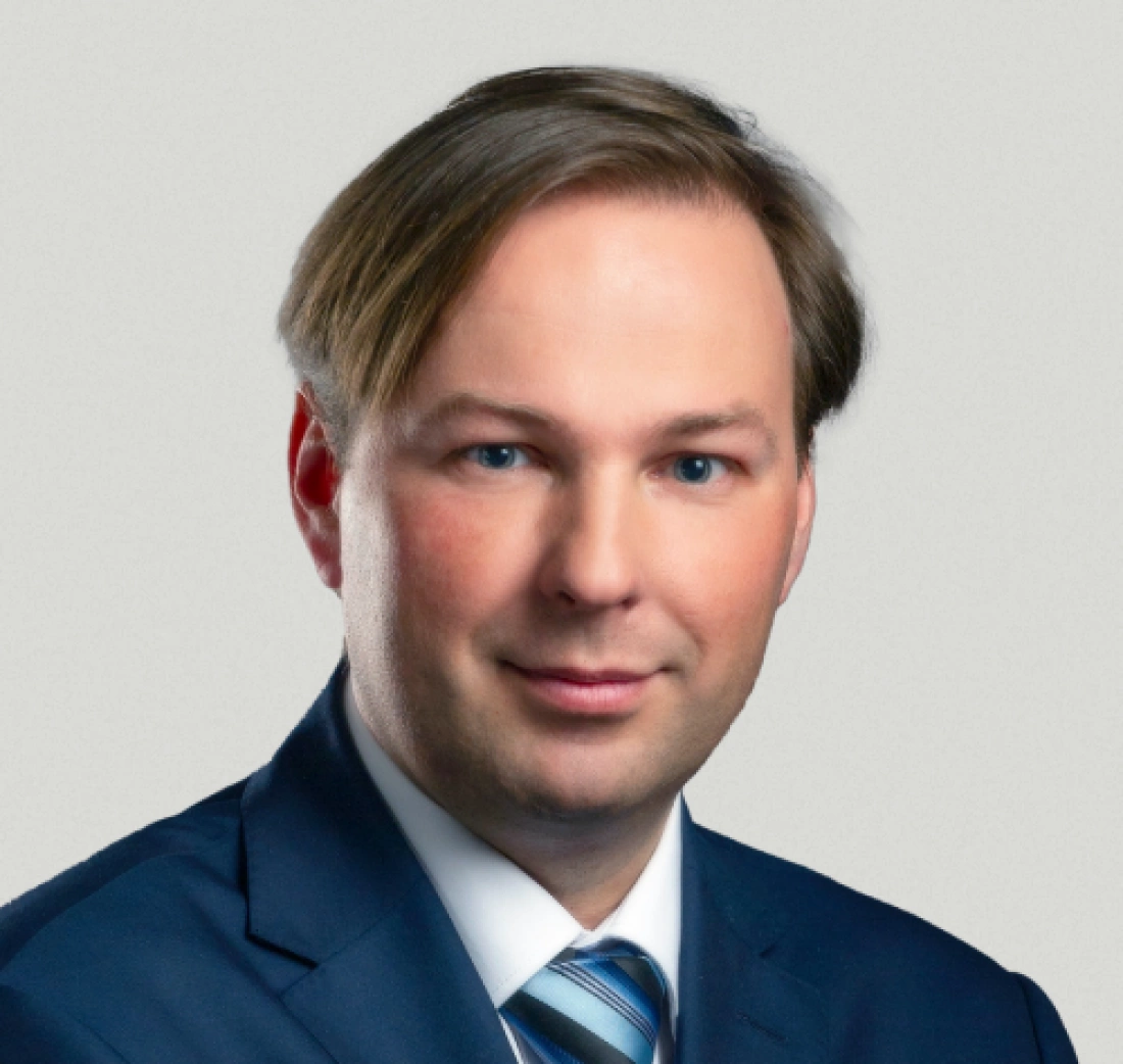 Portret mężczyzny w garniturze, z krótkimi włosami i niebieskimi oczami.