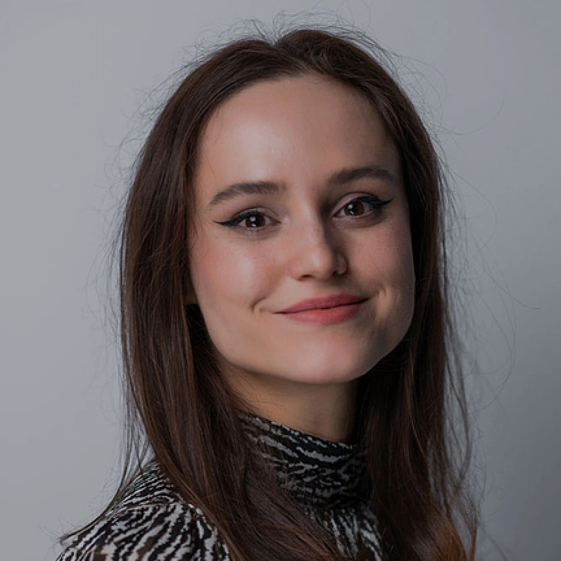 Młoda kobieta uśmiechająca się w stonowanej scenerii.