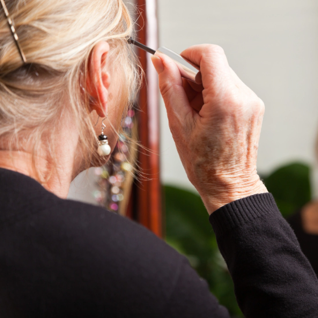 Kobieta maluje brwi przed lustrem.