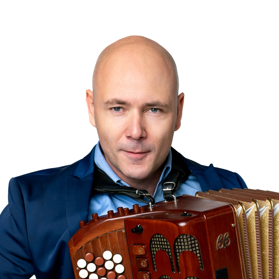 Mężczyzna w garniturze trzyma akordeon, patrząc w stronę obiektywu.