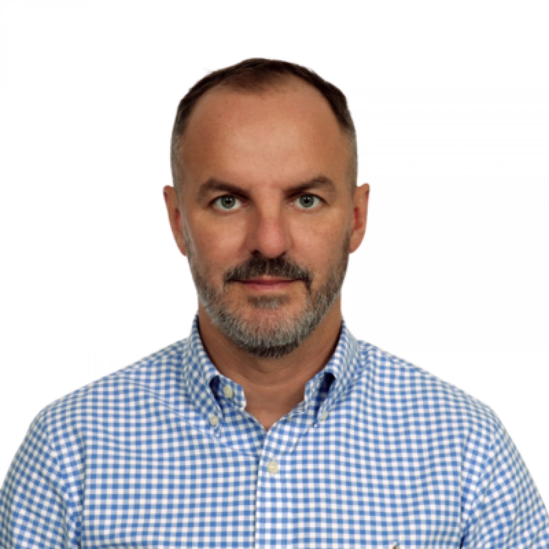 Portret mężczyzny w niebieską kratkę, z zarostem i poważnym wyrazem twarzy.