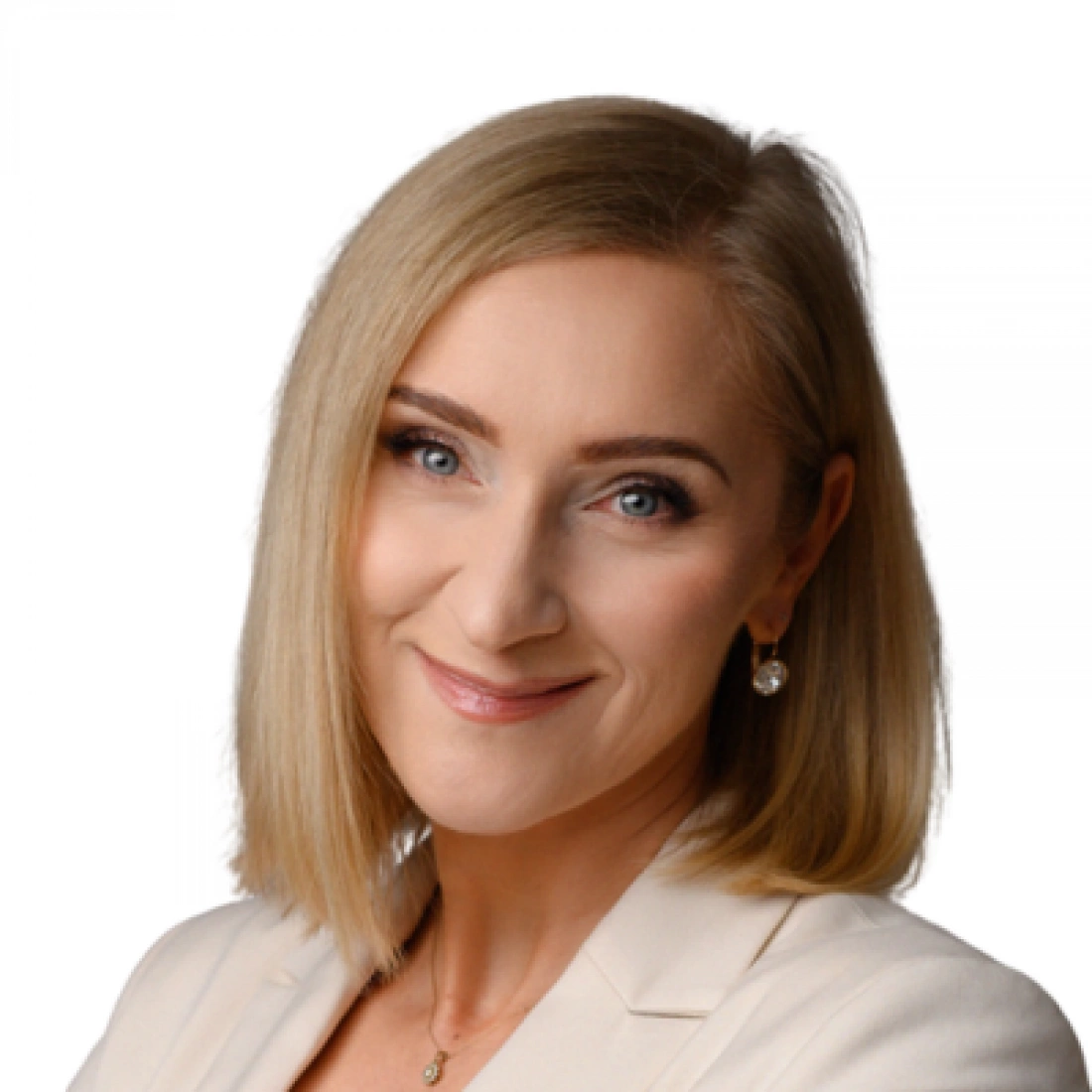 Portret kobiety z krótkimi, blond włosami, w jasnej marynarce, uśmiechającej się.