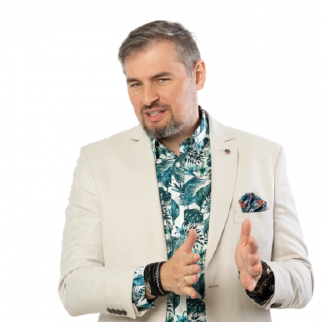 Mężczyzna w jasnym garniturze i wzorzystej koszuli, gestykulujący w trakcie wypowiedzi.