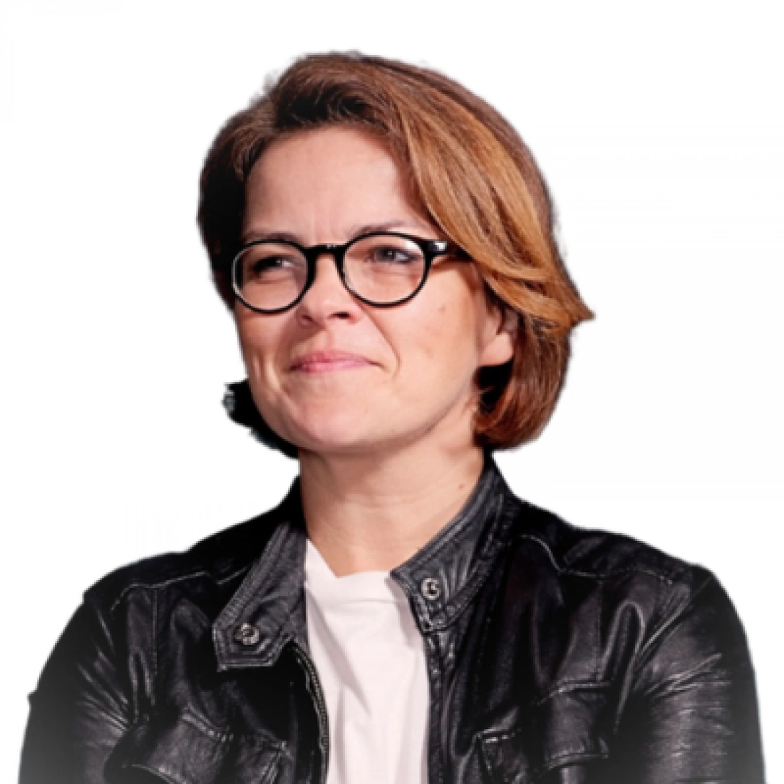 Kobieta o krótkich brązowych włosach, w okularach i czarnej skórzanej kurtce, uśmiecha się.