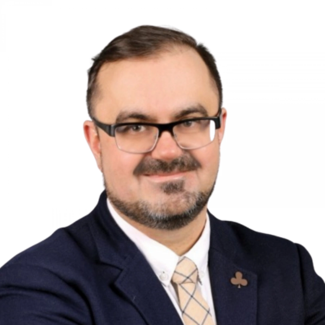 Mężczyzna w okularach, ubrany w garnitur, z uśmiechem na twarzy.