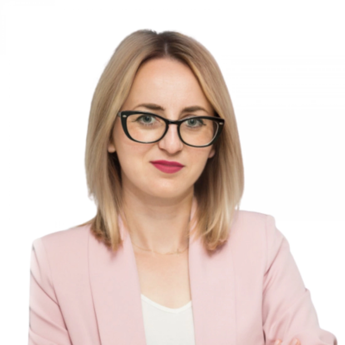 Kobieta w różowej marynarce z okularami, z założonymi rękami.