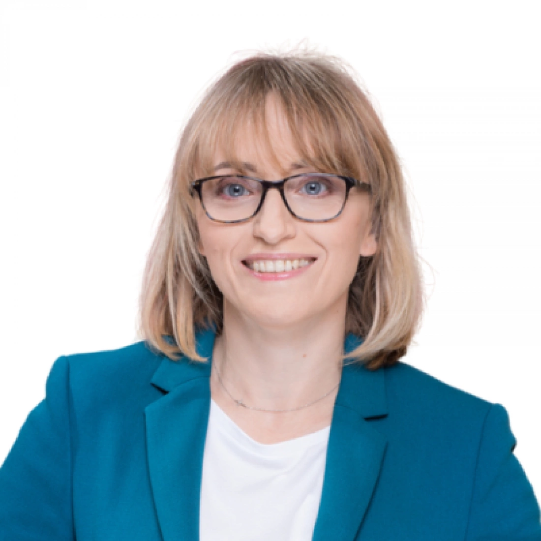 Kobieta w okularach, uśmiechająca się, ubrana w niebieską marynarkę.