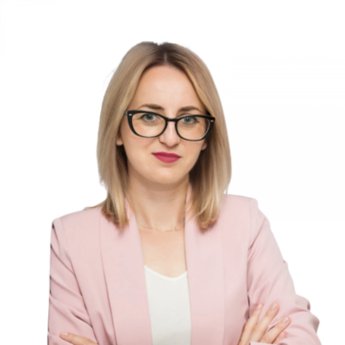 Kobieta w różowym żakiecie z okularami, z założonymi rękami.