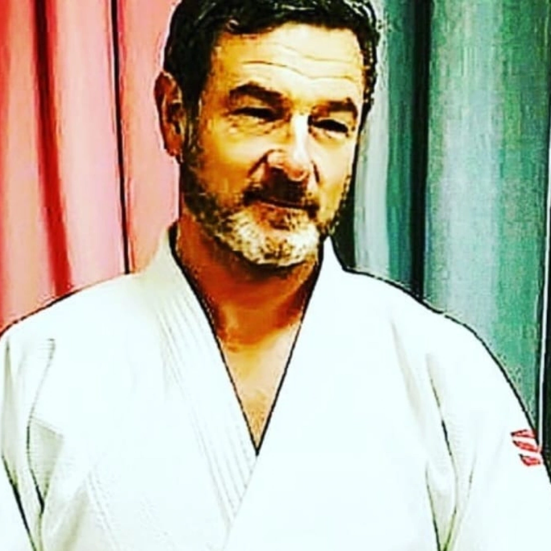 Mężczyzna w kimono, stojący na tle kolorowych zasłon.