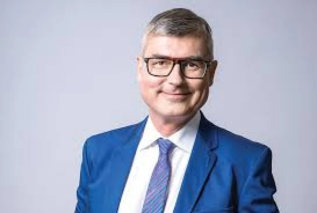 Mężczyzna w eleganckim garniturze, uśmiechający się do kamery.