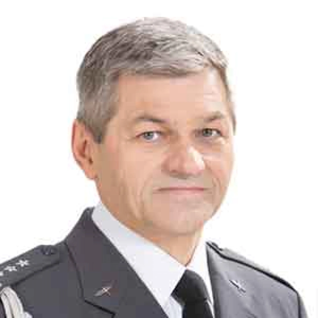 Mężczyzna w mundurze wojskowym z szarymi włosami i uśmiechem.