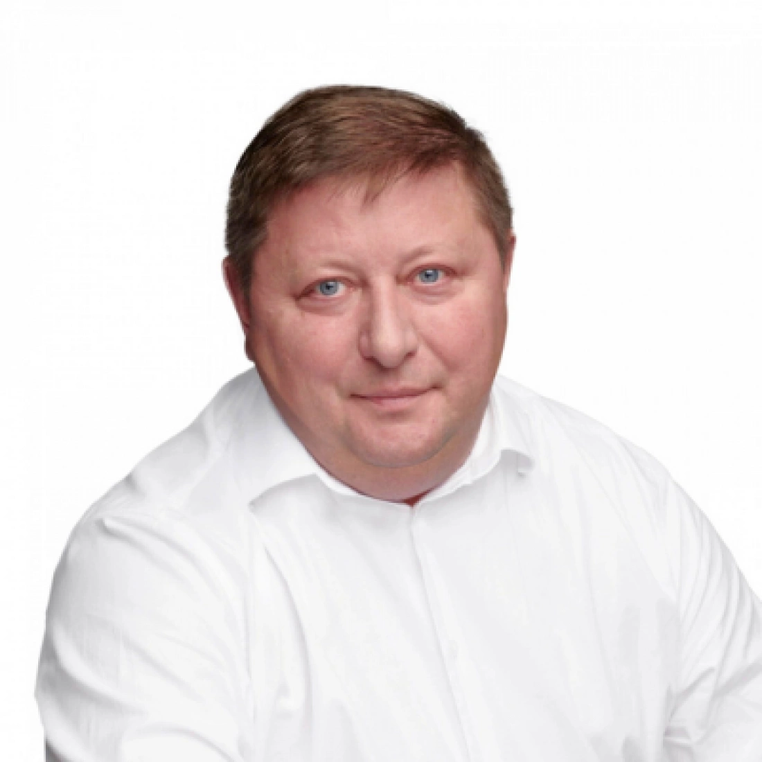 Mężczyzna w białej koszuli, uśmiechający się do kamery.