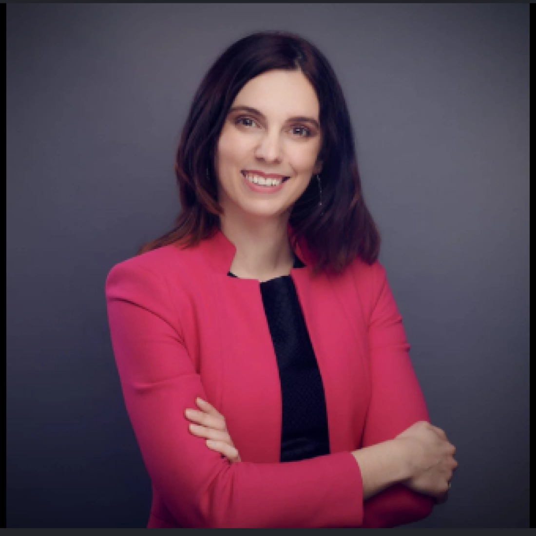 Portret kobiety z długimi ciemnymi włosami, ubranej w zieloną bluzkę i złotą biżuterię, na tle białym.